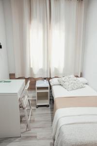 a bedroom with two beds and a desk and a window at Hostal Ruta de Francia in Barcelona