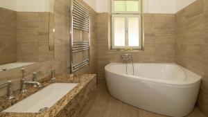 a bathroom with a large white tub and a mirror at Kira Panzió in Lengyeltóti +25 photos