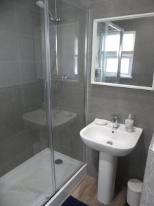 a bathroom with a shower and a sink and a mirror at Flat 3, Willow Court in Llandudno +17 photos