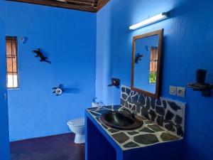 Baño azul con lavabo y espejo en Auberge Le Lagon en Nosy Be