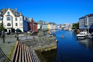 une rivière avec des bateaux dans une ville avec des bâtiments dans l'établissement Near Brosundet, Newly Refurnished, Free Street Parking, à Ålesund