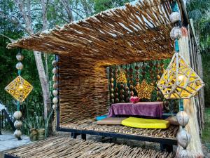 a bed made out of a straw shelter with a table at Phumaihom Resort in Hat Yai