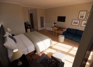 キッツビュールにあるHENRI Country House Kitzbühelのベッドルーム(白いベッド1台、青いソファ付)