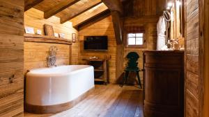 Una gran bañera blanca en una habitación con paredes de madera. en Chalets de l'Alpaga, en Megève