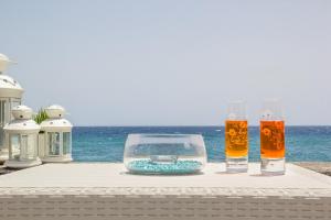 a table with two glasses and a fish bowl on the beach at Sea paradise - il mare sotto la finestra in Riposto