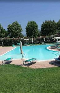 una grande piscina blu con sedie e ombrelloni di Casa della Fattoria, Tuscany Chic Flat a La Cinquantina