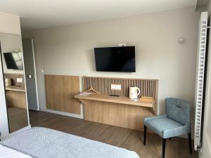 Zimmer mit einem TV, einem Stuhl und einem Bett in der Unterkunft LE RELAIS DES HAYONS 