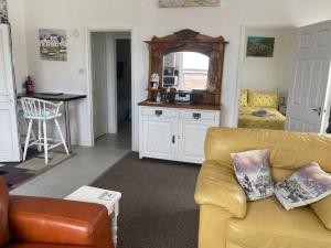 Old Co Op House -Forest of Dean في Bream: غرفة معيشة مع أريكة صفراء ومطبخ