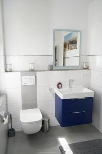 ein Badezimmer mit einem WC, einem Waschbecken und einem Spiegel in der Unterkunft Strandhaus Döse 1 in Cuxhaven