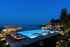 a pool with lounge chairs and umbrellas at night at Agapitos Villas & Guesthouses in Agios Ioannis Pelio