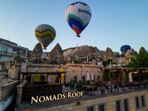 two hot air balloons are flying over a building at Nomads Cave Hotel & Rooftop in Goreme