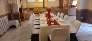 a long table in a room with white chairs at Thokoza guest house in Manzini