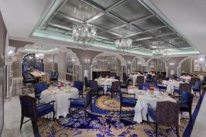 una sala da pranzo con tavoli, sedie e lampadari a braccio di ITC Maurya, a Luxury Collection Hotel, New Delhi a Nuova Delhi