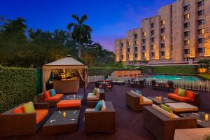 un patio con tavoli, sedie e piscina di ITC Maurya, a Luxury Collection Hotel, New Delhi a Nuova Delhi