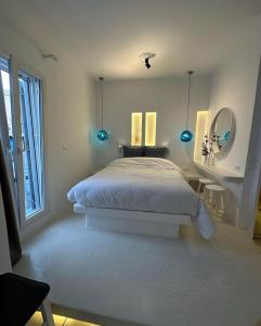 a white bedroom with a bed and a mirror at Studios Eleni I in Tinos
