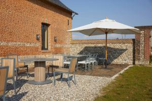 a patio with an umbrella and tables and chairs at Maison Familiale le Maréchal in Doudeville