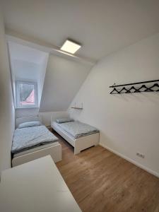 Habitación con 2 camas, paredes blancas y suelo de madera. en Ferienwohnung Jonathan en Coblenza
