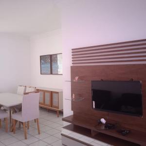 a living room with a television and a dining room table at apartamento em edifício de frente para o mar na praia do morro Guarapari in Guarapari