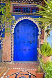 een blauwe deur op een huis met planten bij Hotel Dar Annasr in Chefchaouene