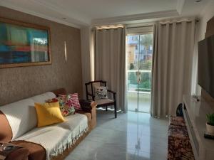 a living room with a couch and a large window at Apto de 2 quartos vista pro mar de Itaúna in Saquarema