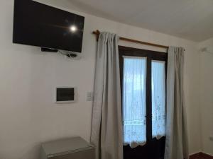 Una habitación con una ventana con cortinas y un televisor de pantalla plana. en LO DE MECHI, en Salta