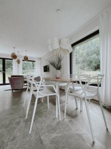 a white dining room with a table and chairs at Cisowy Zakątek in Sasino