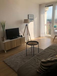 uma sala de estar com uma televisão de ecrã plano e uma mesa em Apartament Nowy Port em Gdansk