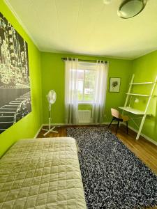 1 dormitorio con paredes verdes, 1 cama y ventana en Centralt belägen villa i Öjebyn, Piteå en Piteå