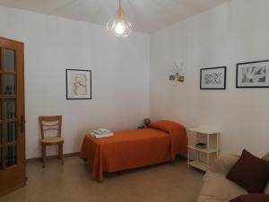 a bedroom with a bed with an orange blanket and a chair at Dimora d'artista in Galatone