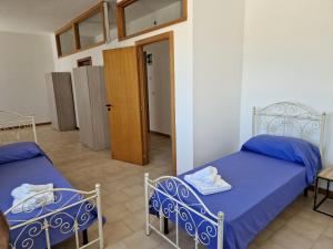a bedroom with two beds and a door to a room at Tuglie Via Palmieri in Tuglie