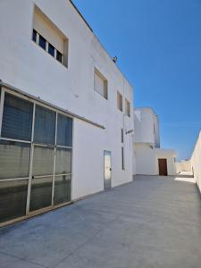 a white building with large windows and a driveway at Tuglie Via Palmieri in Tuglie