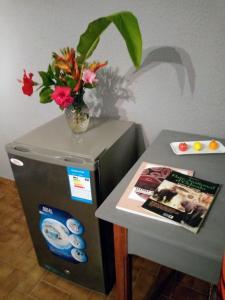 einen Tisch mit einer Vase Blumen auf einem Kühlschrank in der Unterkunft La Chambre de Cosy in Libreville