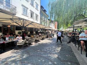 a group of people walking down a street with tables and chairs at Divine Nest in Ljubljana