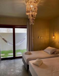 a bedroom with two beds and a chandelier and a window at Pousada Ybitu in São Miguel do Gostoso