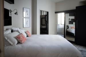 - une chambre avec un grand lit blanc et des oreillers dans l'établissement LeParticulier - L'Amiral, à Chartres