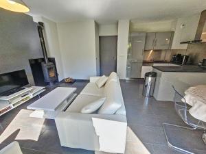 a living room with a white couch and a kitchen at Appartement 4-6 couchages in Aulus-les-Bains