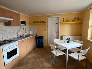 uma cozinha com uma mesa e uma mesa e cadeiras brancas em Pension am Elberadweg - Rogätz 