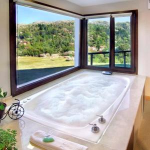 a large bath tub in a room with a large window at Suites de la Colina in La Cumbrecita