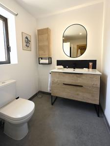 een badkamer met een toilet, een wastafel en een spiegel bij Les Agapanthes de Gordes in Gordes