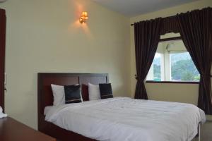 a bedroom with a large white bed with a window at Hotel Toba Shanda By Helocus in Parapat