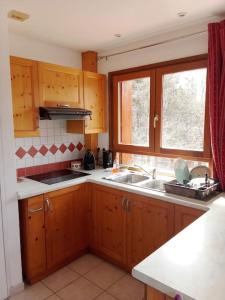 a kitchen with wooden cabinets and a sink and a window at Appartement des cimes du Granier in Les Déserts