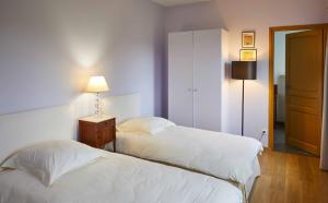 1 Schlafzimmer mit 2 Betten, einer Lampe und einer Tür in der Unterkunft La Maison de Charlotte in Doudeville