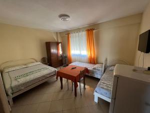 een kamer met twee bedden en een tafel erin bij Rexhina Apartments in Durrës