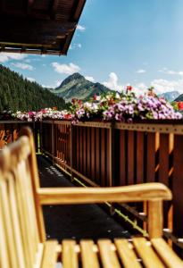 un banco de madera sentado en un balcón con flores en Pension Uga en Damuls