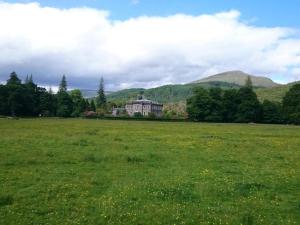 a large field with a large house in the distance at Highland Bridge Hotel in Spean Bridge