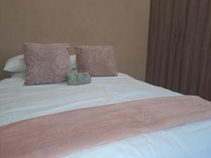 Cama con sábanas y almohadas rosas y blancas en Cozy Airport Stay, en Kempton Park