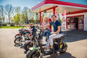 a group of people riding motorcycles in front of a gas station at Scandi Resort in Zator