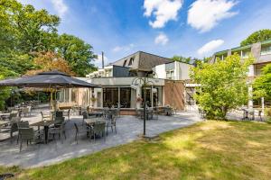 un patio con mesas, sillas y una sombrilla en Fletcher Hotel-Restaurant De Scheperskamp en Lochem