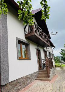 uma casa branca com varanda e escadas em Smerichka em Bukovel