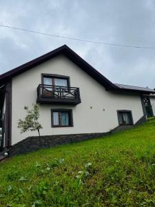 a white house with a balcony on a hill at Smerichka in Bukovel